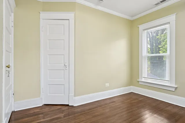 a view of an empty room with wooden floor and a window