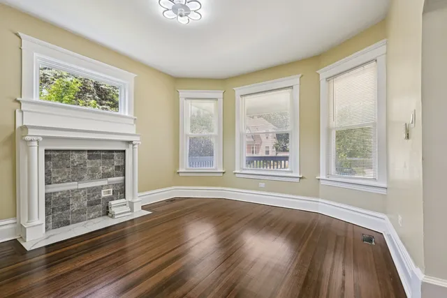 a view of wooden floor fire place and windows in a room