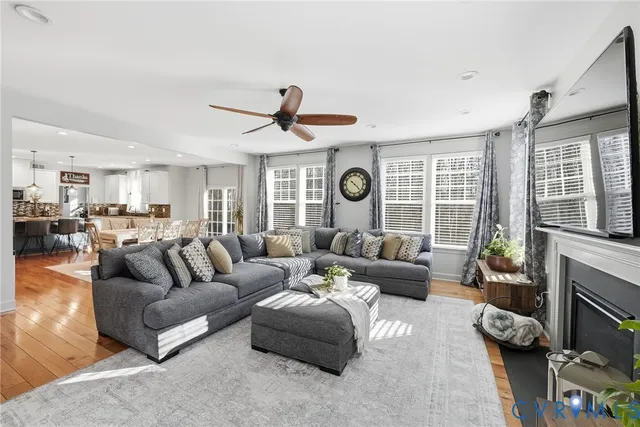 a living room with furniture kitchen view and a wooden floor