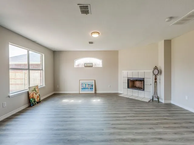 an empty room with wooden floor fireplace and windows