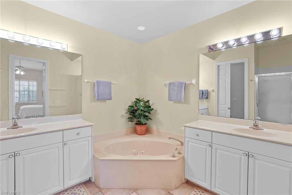 795 Bentwater Circle, Unit 203 Naples, FL 34108 - Photo 16 of 33 a bathroom with a white tub a sink and mirror