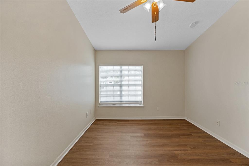 4360 South Kirkman Road, Unit 4 Orlando, FL 32811 - Photo 14 of 21 an empty room with wooden floor chandelier fan and windows