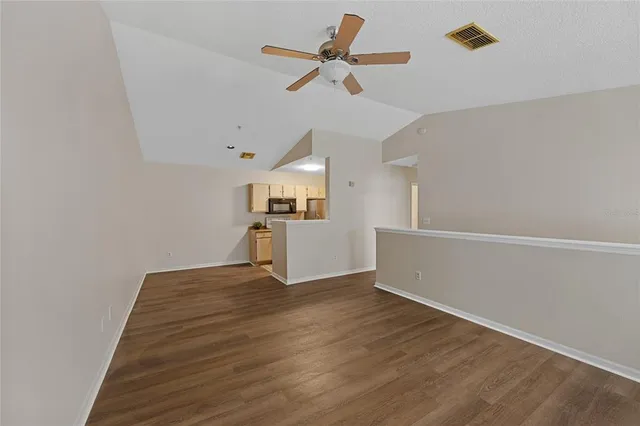 a view of empty room with wooden floor and ceiling fan