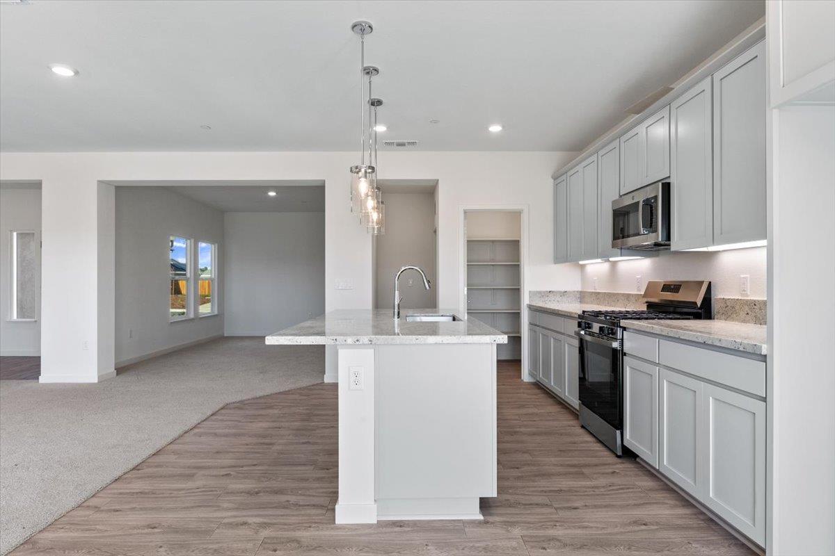 271 Piper Lane Colusa, CA 95932 - Photo 14 of 24 a kitchen with stainless steel appliances granite countertop a stove top oven a sink dishwasher a refrigerator and a dining table with wooden floor