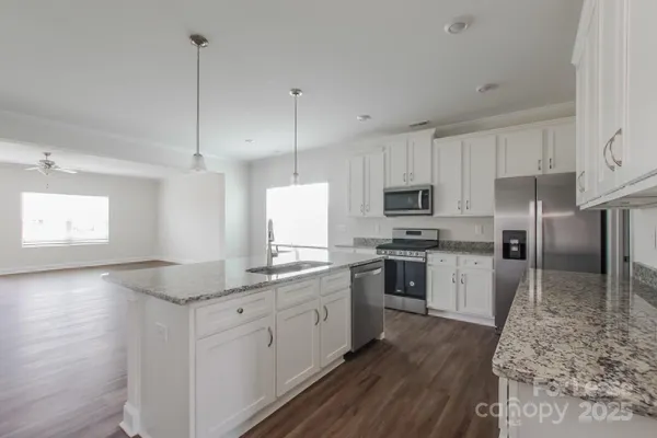 a kitchen with granite countertop a sink stainless steel appliances and white cabinets