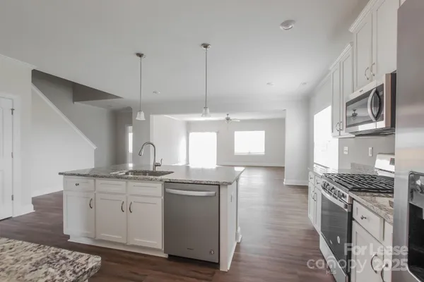 a kitchen with a sink stove cabinets and wooden floor