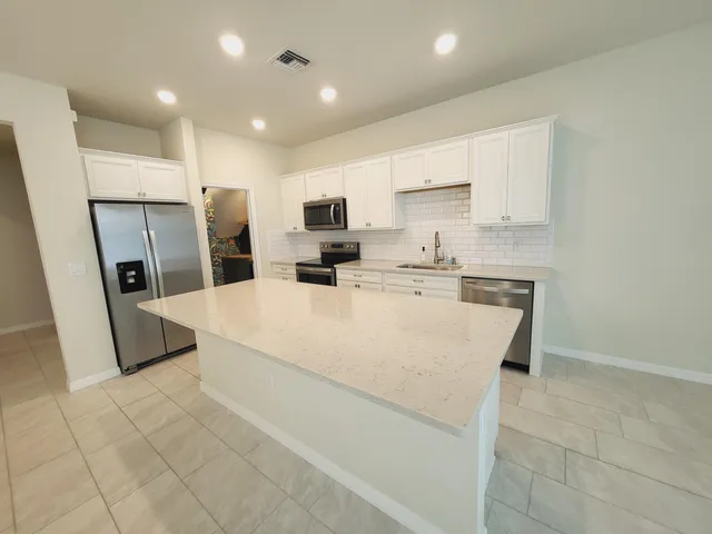 a large white kitchen with cabinets stove a sink and a refrigerator