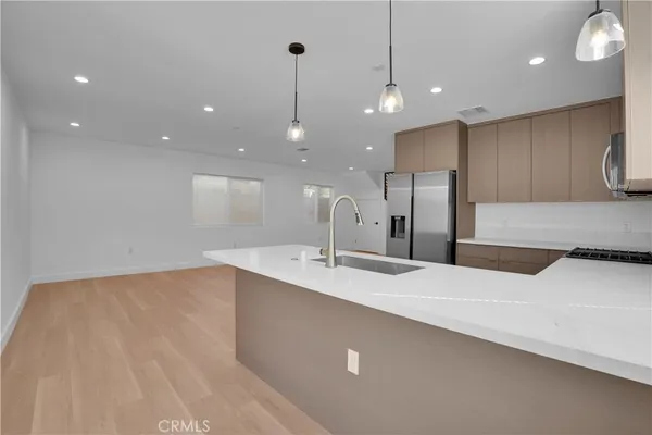 a large kitchen with stainless steel appliances a large counter top a sink and a refrigerator
