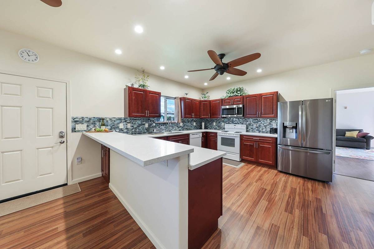 4598 Pueo Road, Unit B Kekaha, HI 96752 - Photo 6 of 27 a kitchen with stainless steel appliances a stove a refrigerator a oven a sink with island and chairs