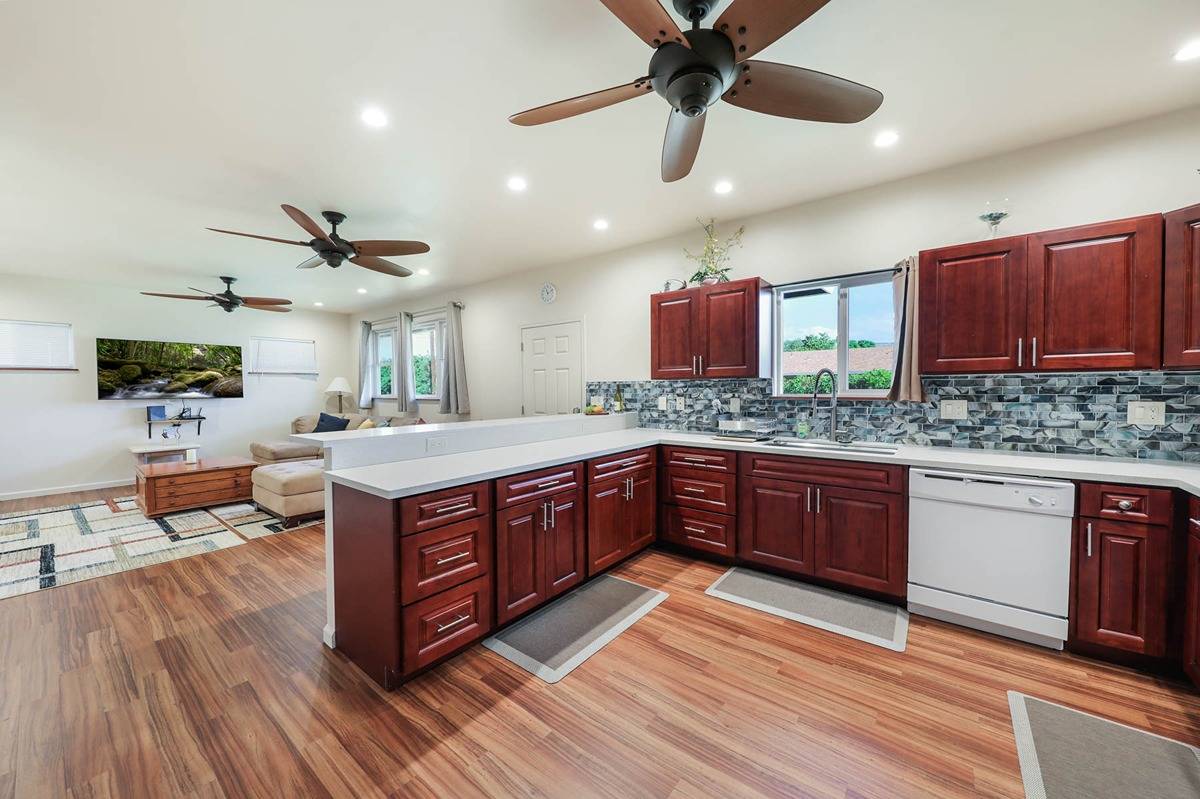 4598 Pueo Road, Unit B Kekaha, HI 96752 - Photo 8 of 27 a large kitchen with stainless steel appliances granite countertop a sink dishwasher stove and wooden floor