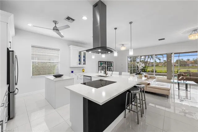 a kitchen with a sink a counter top space and living room view