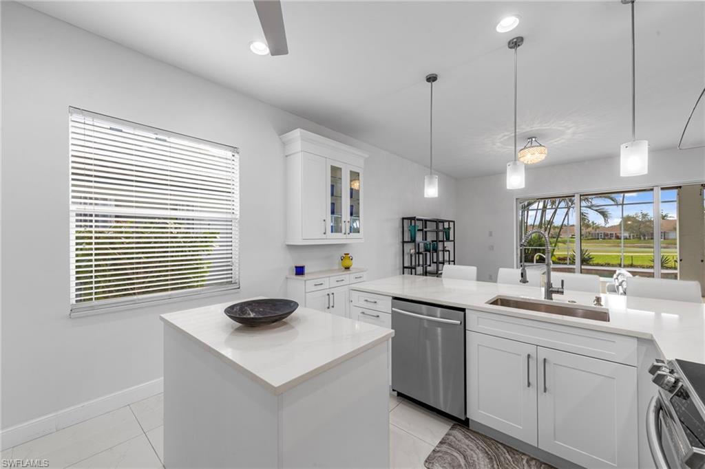 21550 Berwhich Run Estero, FL 33928 - Photo 15 of 50 a kitchen with a sink a stove a window cabinets and stainless steel appliances