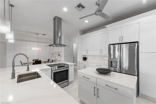 a kitchen with kitchen island stainless steel appliances a sink a stove and refrigerator