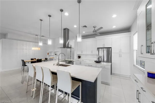 a kitchen with stainless steel appliances kitchen island granite countertop a sink a stove a refrigerator and white cabinets with wooden floor