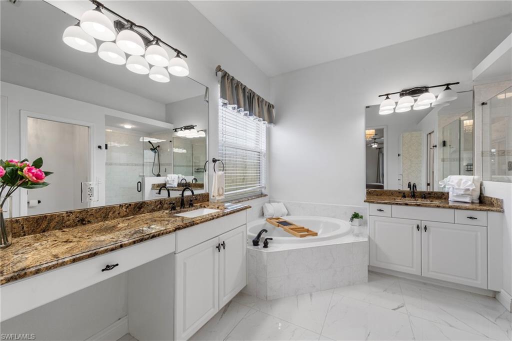 21550 Berwhich Run Estero, FL 33928 - Photo 24 of 50 a large bathroom with a granite countertop double vanity sink a bathtub and a mirror