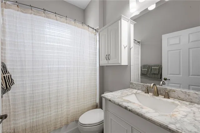 a bathroom with a granite countertop sink a toilet and shower