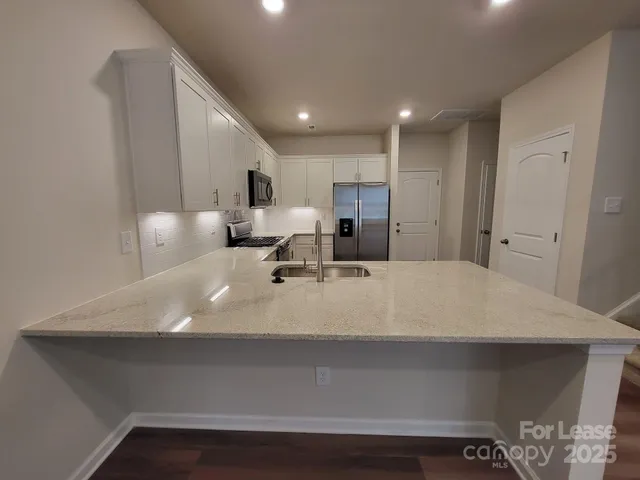 a large white kitchen with a sink a counter space and cabinets
