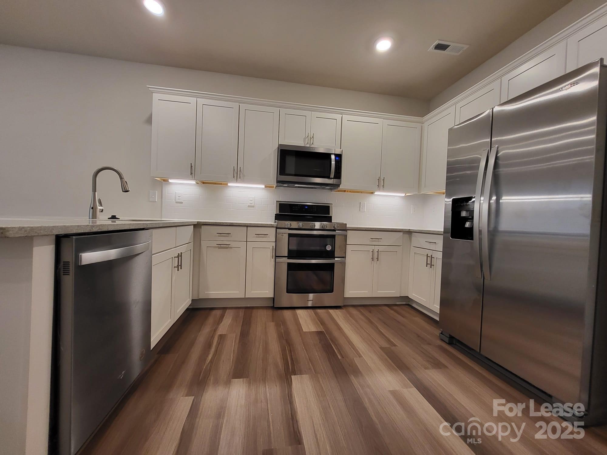 3511 Glenn Hope Way Matthews, NC 28104 - Photo 4 of 17 a kitchen with white cabinets stainless steel appliances and a refrigerator