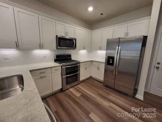 a kitchen with granite countertop a refrigerator stove and microwave