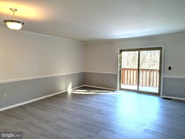 a view of a kitchen with kitchen island wooden floor and stainless steel appliances