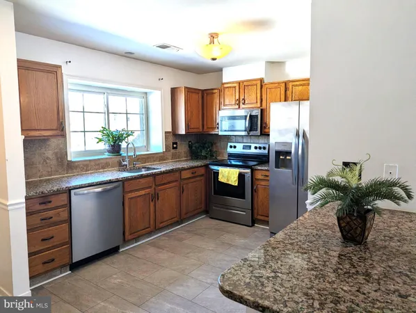 a large kitchen with stainless steel appliances granite countertop a stove a sink and a refrigerator