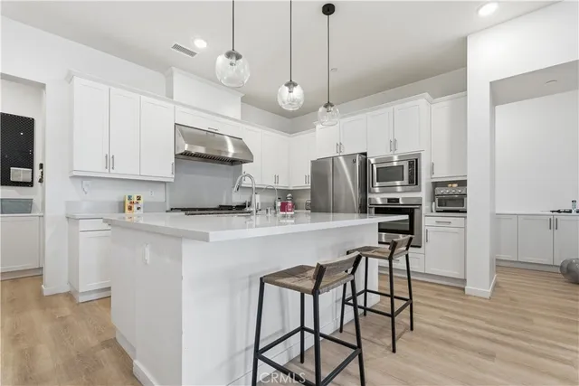 a kitchen with stainless steel appliances a table chairs refrigerator and microwave