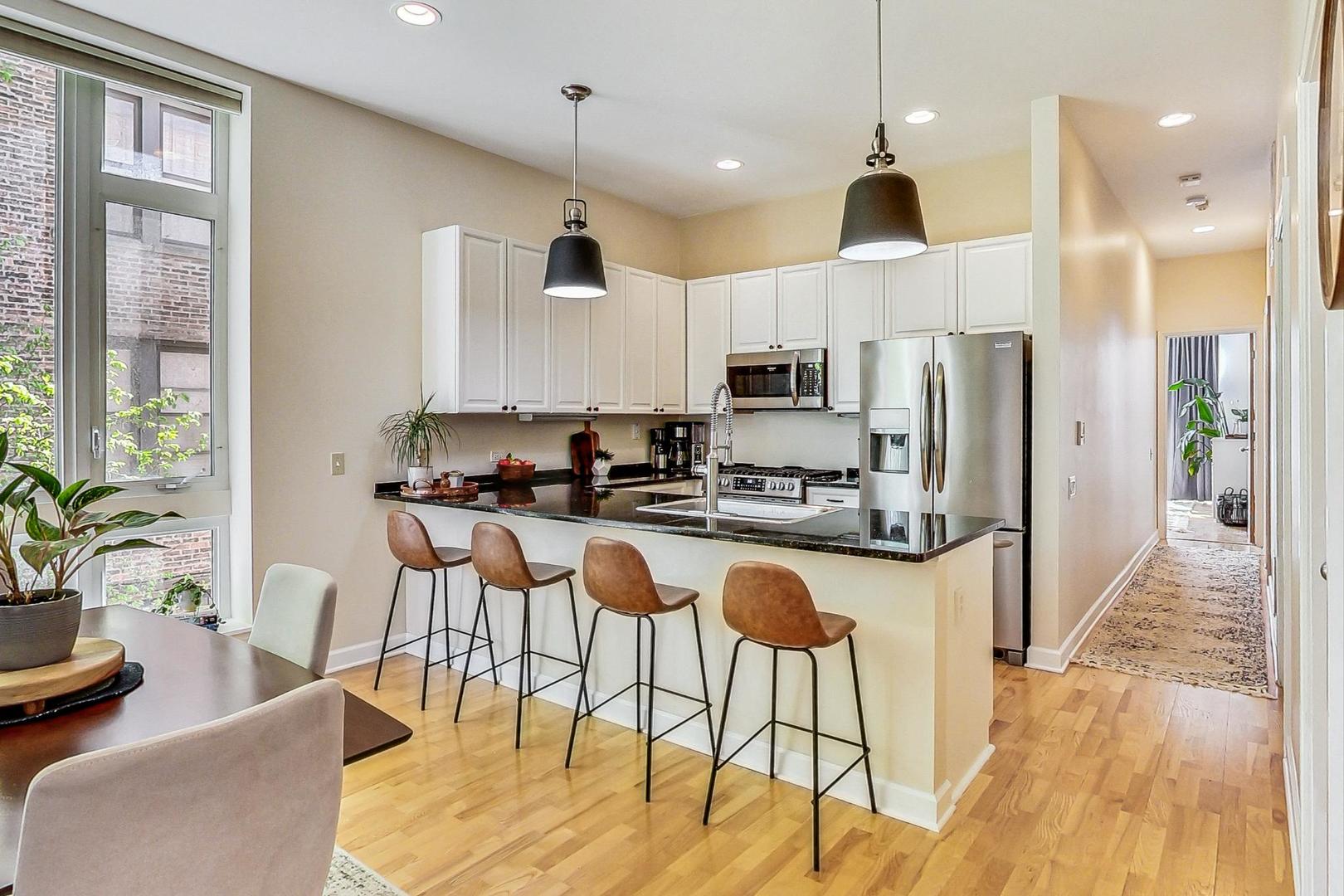 4150 North Sheridan Road, Unit 2S Chicago, IL 60613 - Photo 11 of 29 a kitchen with stainless steel appliances granite countertop a stove a refrigerator a kitchen island a dining table and chairs with wooden floor