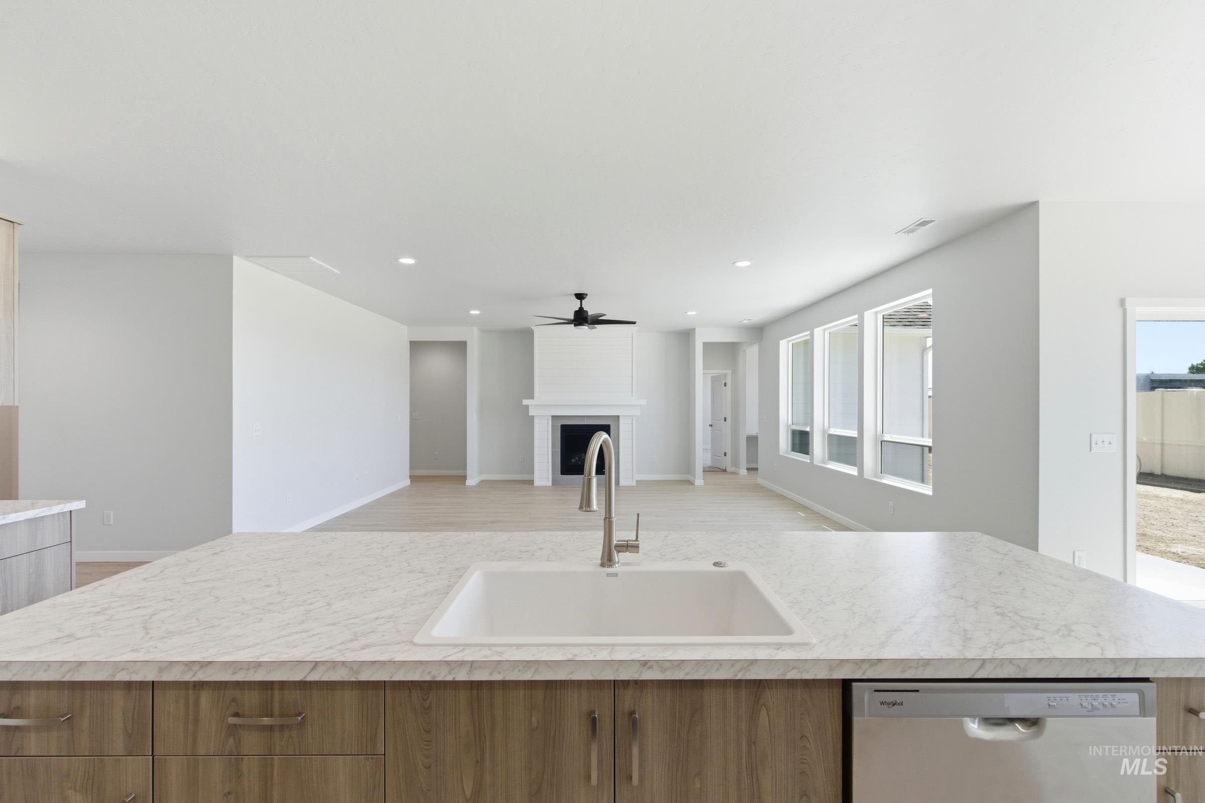 13663 Redway Court Caldwell, ID 83607 - Photo 5 of 32 Kitchen island featuring a single-basin sink with a gooseneck faucet, light-toned countertop, and wood-finish cabinetry