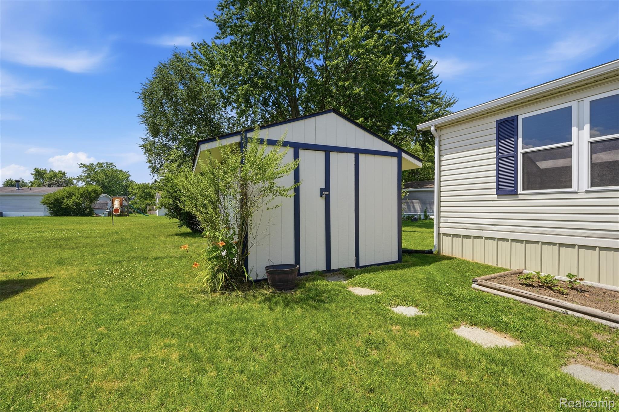 4634 Butternut Street Clarkston, MI 48348 - Photo 27 of 28 Expansive green lawn with a storage shed featuring white siding and dark trim