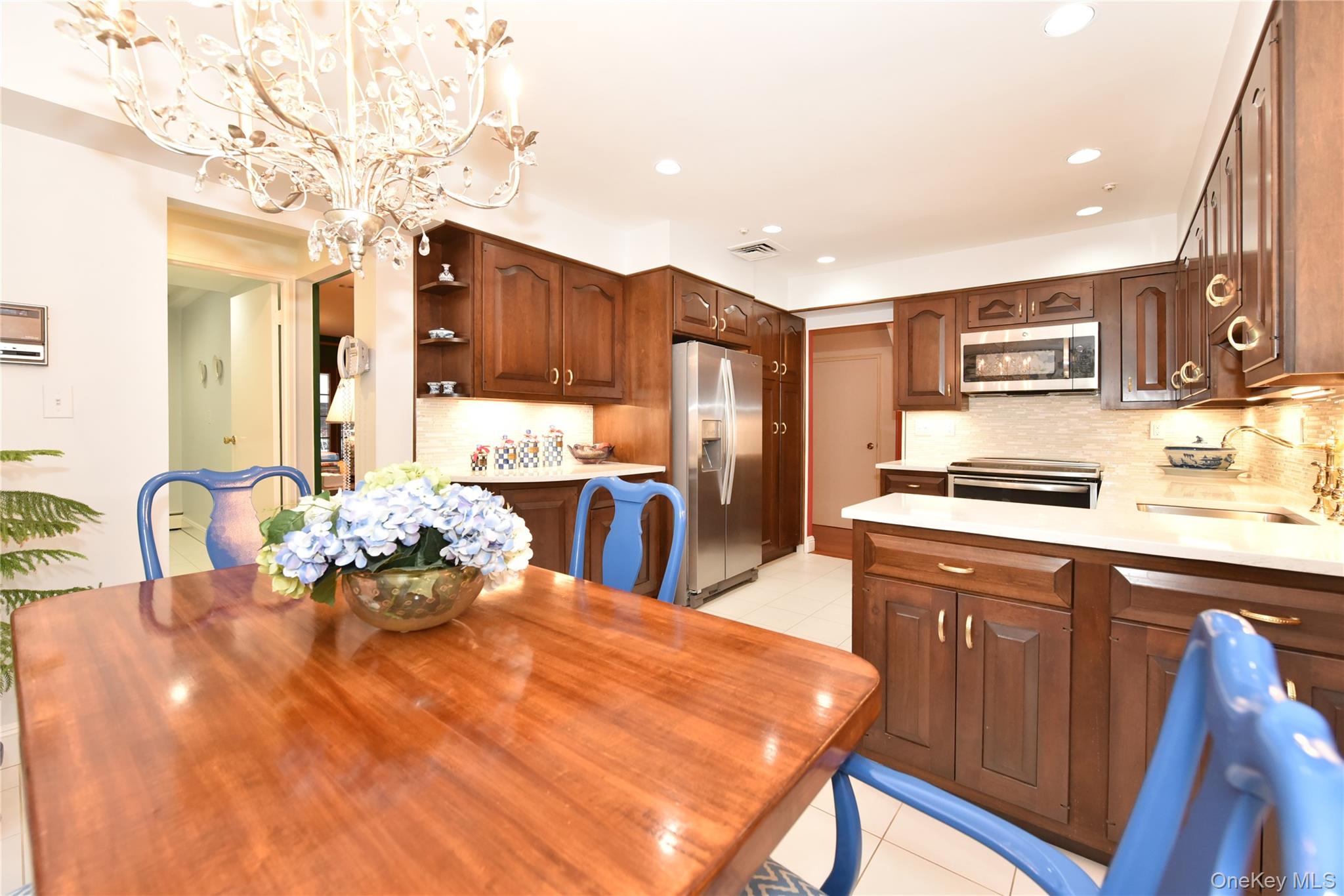 11 Joy Drive Manhasset Hills, NY 11040 - Photo 10 of 41 a kitchen with stainless steel appliances kitchen island granite countertop a table chairs in it and wooden floors