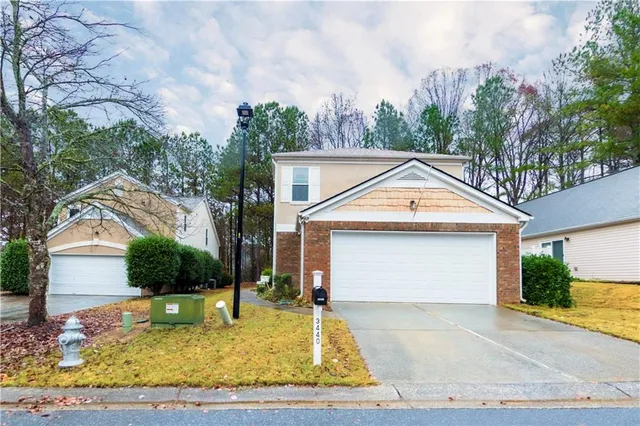 a view of a white house with a small yard and large tree