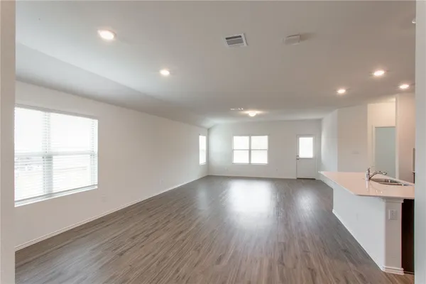 an empty room with wooden floor and windows