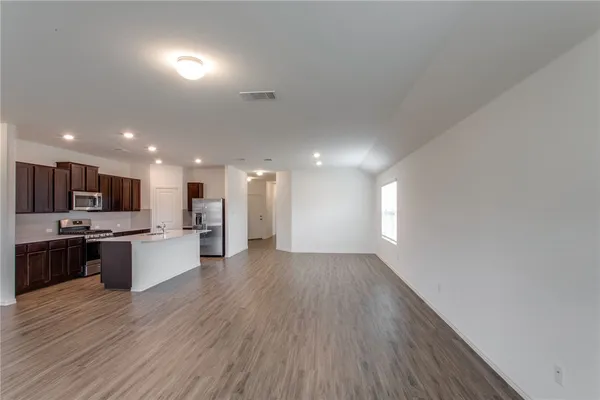 a kitchen with stainless steel appliances a refrigerator a stove top oven a sink and dishwasher with wooden floor