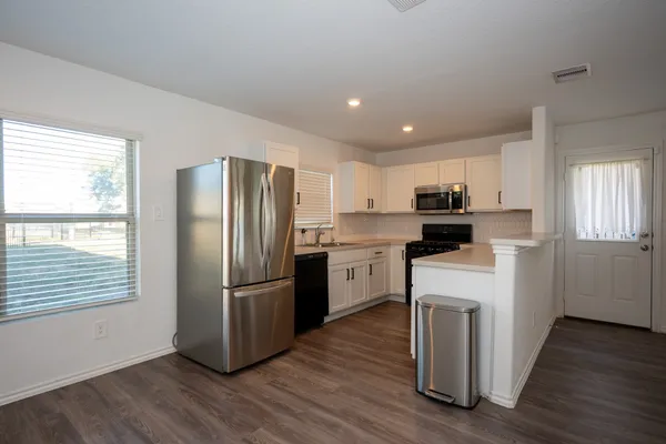 a kitchen with a refrigerator sink and cabinets