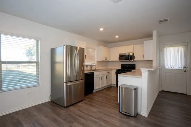 a kitchen with a refrigerator sink and cabinets