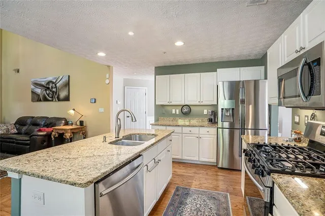 a kitchen with stainless steel appliances granite countertop a sink stove and refrigerator
