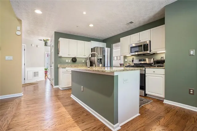 a kitchen with stainless steel appliances granite countertop a stove top oven a sink and a refrigerator