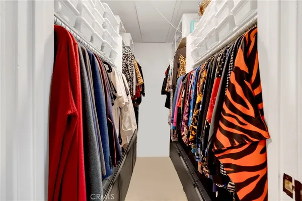 a view of walk in closet with clothes and shoes