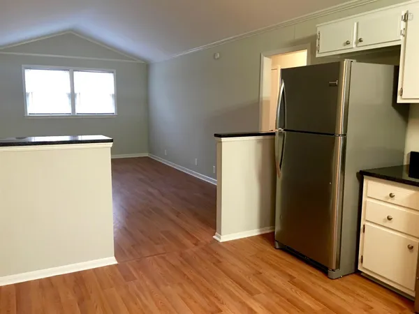 a view of a kitchen with wooden floor and a refrigerator