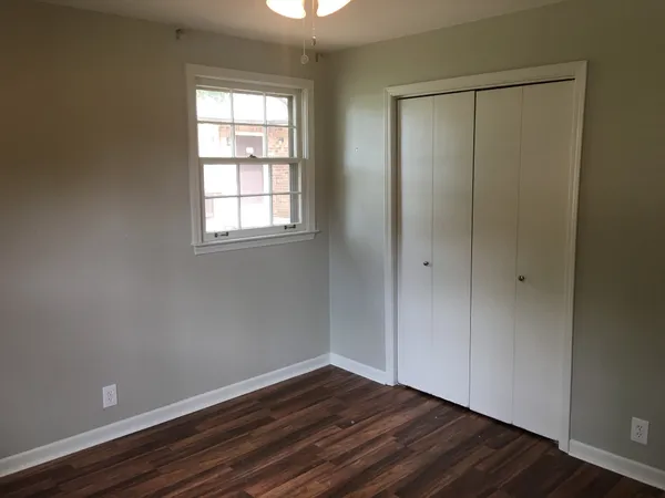 a view of an empty room with wooden floor and a window