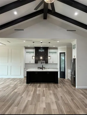 a view of kitchen with stainless steel appliances wooden floor and chandelier