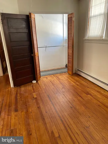 a view of an empty room with wooden floor and window