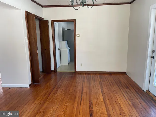 a view of an empty room with wooden floor and closet