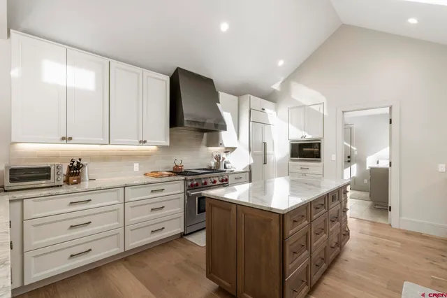 a kitchen with kitchen island granite countertop a sink a stove and cabinets
