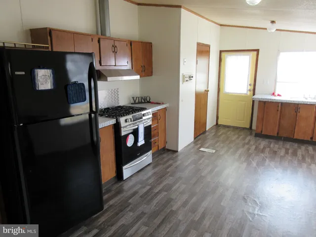 a kitchen with stainless steel appliances granite countertop a refrigerator a stove and a wooden floors