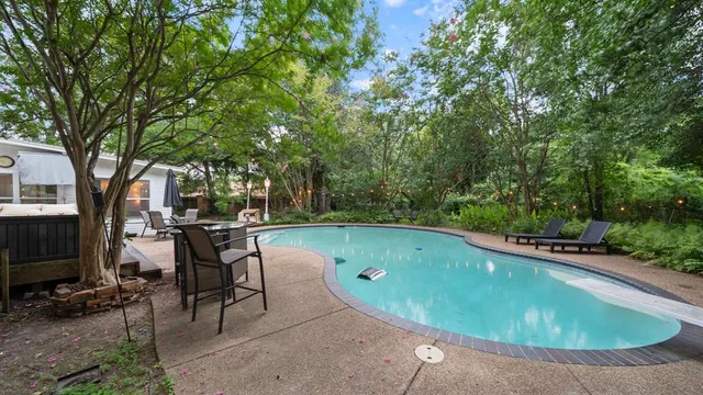 a view of a swimming pool with lawn chairs under an umbrella