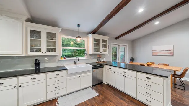a kitchen with granite countertop a sink window and cabinets