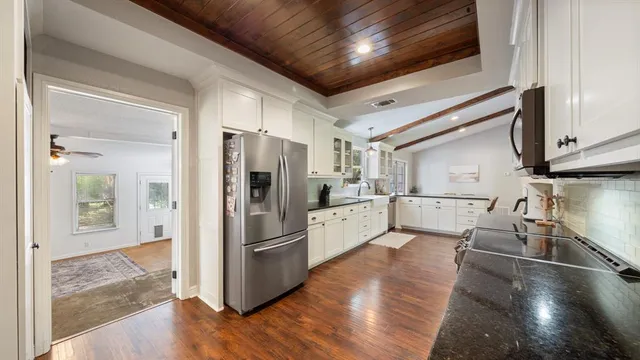 a kitchen with stainless steel appliances a refrigerator a sink a stove and white cabinets with wooden floor