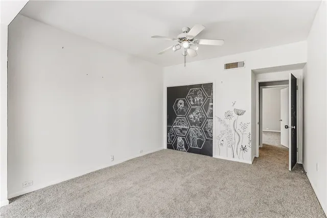 a view of a hallway with closet and chandelier fan