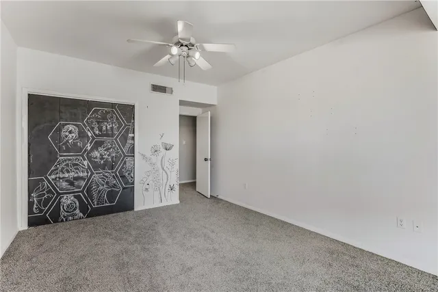 an empty room with windows and fan